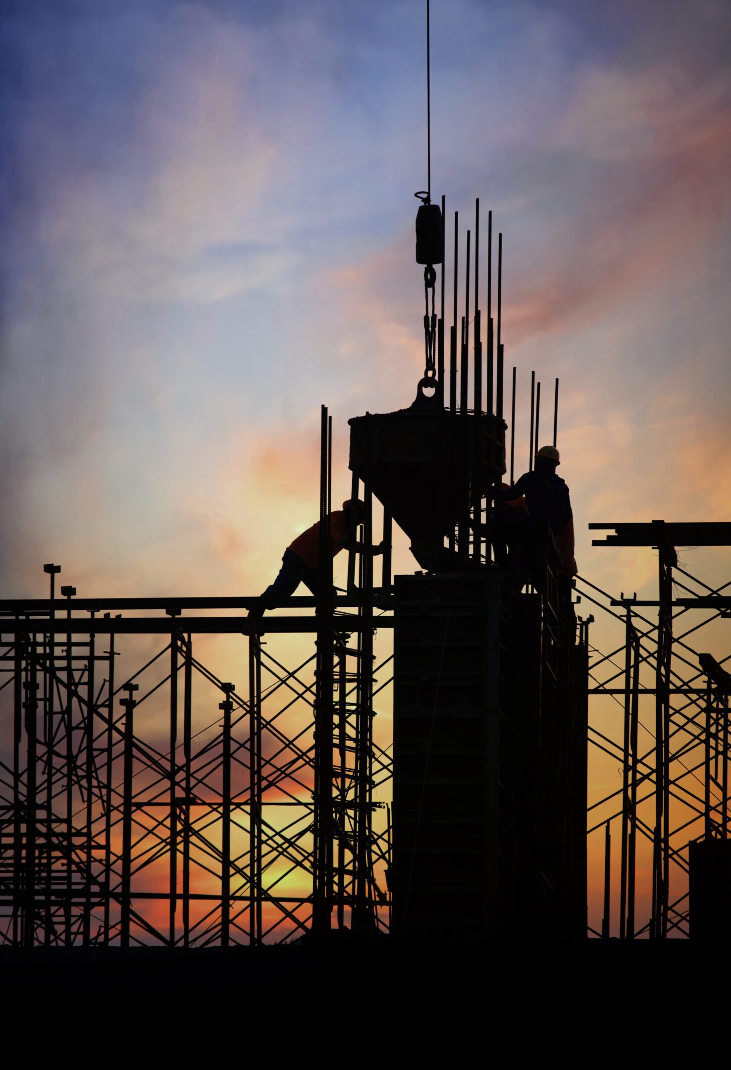 Silhouette of a construction worker on a building frame at sunset.