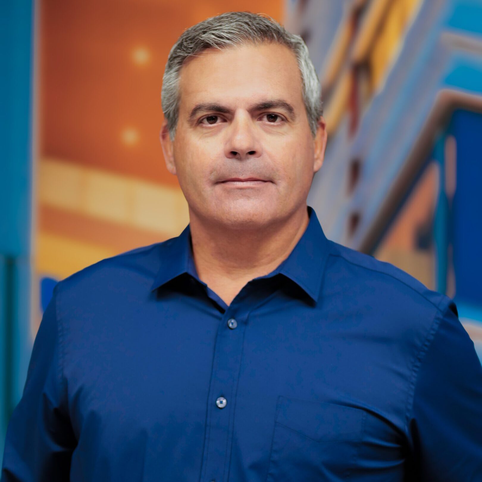 Confident man in a blue shirt posing for a professional portrait.