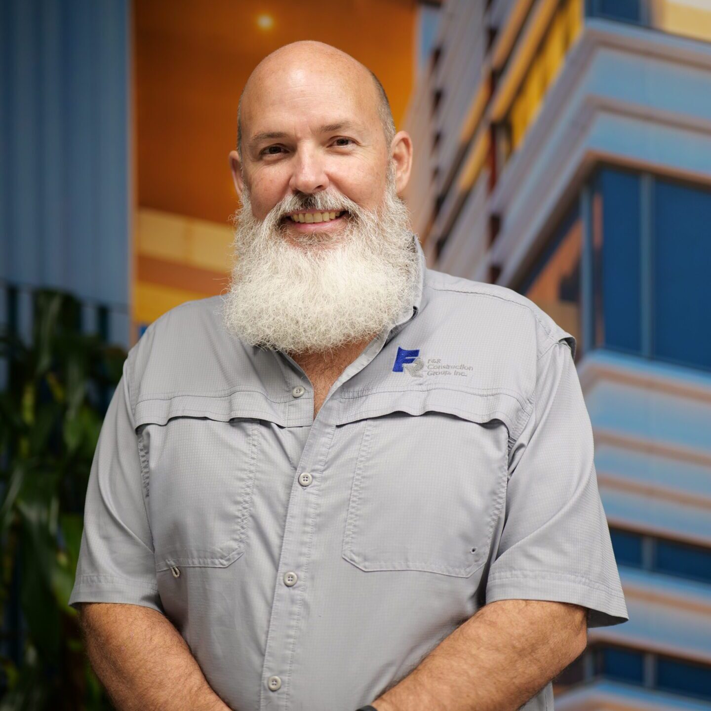Smiling bald man with a full white beard in a gray shirt.